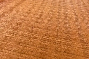Nahaufnahme einer Holzmaserung mit geriegelter Struktur und warmer brauner Tönung.