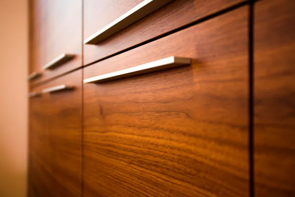 Moderne Schrankfronten aus edlem Holz mit Metallgriffen und natürlicher Maserung.