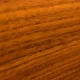 Detailaufnahme einer warmen, goldbraunen Teakholz-Oberfläche mit feiner Holzmaserung.