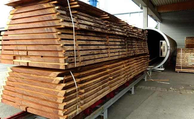 Holzstapel Gestapelte Holzbohlen auf Schienenwagen vor einer Vakuum Trockenkammer auf dem Betriebsgelände von WOB Timber.